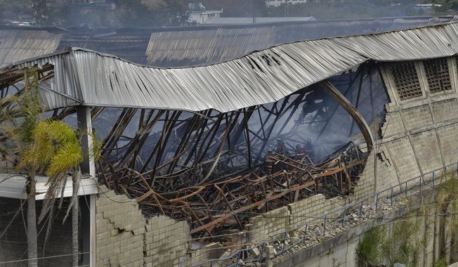 Firefighters work in the aftermath of a fire at a warehouse of the National Electoral Council where tens of thousands of voting machines and fingerprint readers were destroyed, in Caracas, Venezuela, Monday, March 9, 2020. Government officials are vowing not to let the fire deter their quest to hold legislative elections this year. (AP Photo/Matias Delacroix)