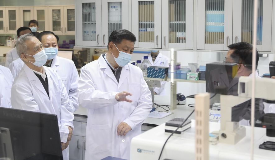 In this Monday, March 2, 2020, photo released by Xinhua News Agency, Chinese President Xi Jinping, centre, wearing a protective face mask, talks to a medical staff member during his visit to the Academy of Military Medical Sciences in Beijing. As the rest of the world grapples with a burgeoning virus outbreak, China's ruling Communist Party has turned to its propaganda playbook to portray its leader as firmly in charge, leading an army of health workers in a "people's war" against the disease. (Ju Peng/Xinhua via AP)
