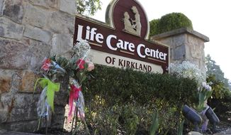 Flowers left next to the sign that marks the entrance to the parking lot of the Life Care Center in Kirkland, Wash. are shown Monday, March 9, 2020, near Seattle. The nursing home is at the center of the outbreak of the COVID-19 coronavirus in Washington state. (AP Photo/Ted S. Warren)