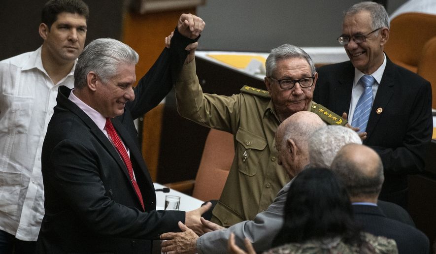 Raul Castro, First Secretary of the Communist Party and former president raises the hand of Cuba&#x27;s president Miguel Diaz-Canel, right, during the closing session at the National Assembly of Popular Power in Havana, Cuba, Saturday, Dec. 21, 2019. (AP Photo / Ramon Espinosa)