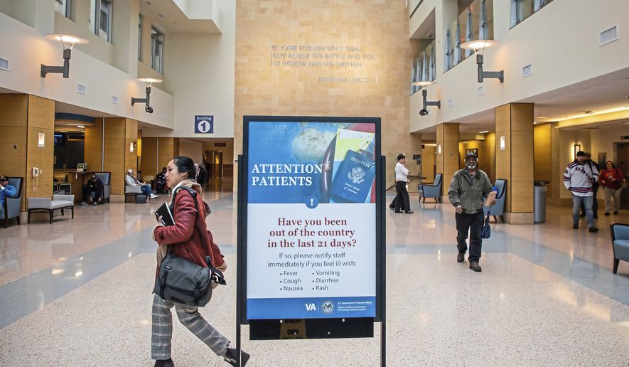 A sign about traveling greets incoming patients at the the U.S. Department of Veterans Affairs Pittsburgh Healthcare System University Drive campus, Tuesday, March 10, 2019, in Pittsburgh. The Pittsburgh VA said by the end of the week it will begin screening every person, whether a patient or not, who comes into its facilities for the novel coronavirus, using questions about symptoms and travel. (Andrew Rush/Pittsburgh Post-Gazette via AP)