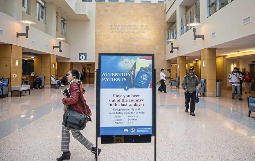 A sign about traveling greets incoming patients at the the U.S. Department of Veterans Affairs Pittsburgh Healthcare System University Drive campus, Tuesday, March 10, 2019, in Pittsburgh. The Pittsburgh VA said by the end of the week it will begin screening every person, whether a patient or not, who comes into its facilities for the novel coronavirus, using questions about symptoms and travel. (Andrew Rush/Pittsburgh Post-Gazette via AP)