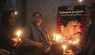 In this Oct. 17, 2020, photo, Pakistani civil society activists hold candle vigil to pay tribute to Aziz Memon in Hyderabad, Pakistan. In Pakistan, being a dissident or even raising a critical voice is dangerous business. Rights groups say that despite the election in 2018 of a civilian government, the army still rules from behind with an iron fist. (AP Photo/Pervez Masih)