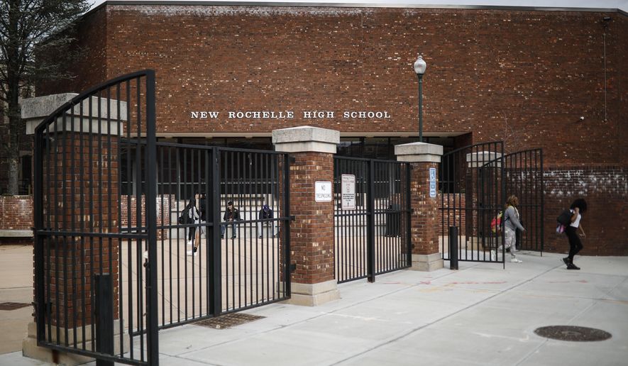 Students leave New Rochelle High School after classes are dismissed, Tuesday, March 10, 2020, in New York. State officials are shuttering schools and houses of worship for two weeks in part of the New York City suburb New Rochelle and sending the National Guard there to help respond to what appears to be the nation's biggest cluster of coronavirus cases. (AP Photo/John Minchillo)