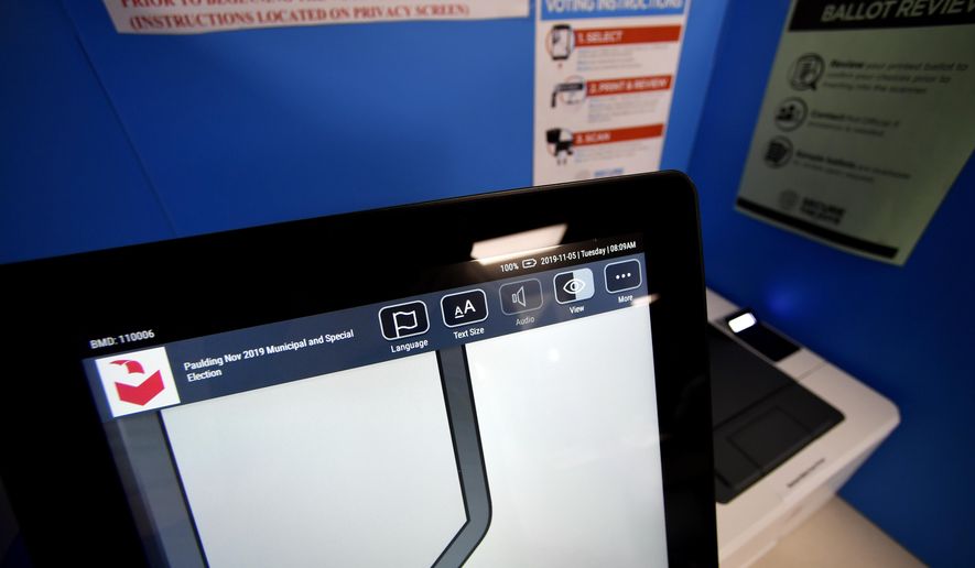 In this Tuesday, Nov. 5, 2019 photo, a touchscreen voting machine and printer are seen in a voting booth, in Paulding, Ga. Georgia's state election board has scheduled an emergency hearing Wednesday, March 11, 2020, to determine whether a county election board violated state laws and election rules when it voted to use hand-marked paper ballots instead of the state's new voting machines for the presidential primary. (AP Photo/Mike Stewart)