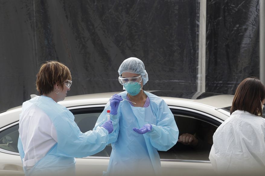 Health care personnel test a person in the passenger seat of a car for coronavirus at a Kaiser Permanente medical center parking lot in San Francisco, Thursday, March 12, 2020. (AP Photo/Jeff Chiu)