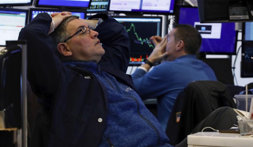 A pair of traders work in their booth on the floor of the New York Stock Exchange, Thursday, March 12, 2020. The deepening coronavirus crisis is sending stocks into another alarming slide on Wall Street, triggering a brief, automatic shutdown in trading for the second time this week. (AP Photo/Richard Drew)