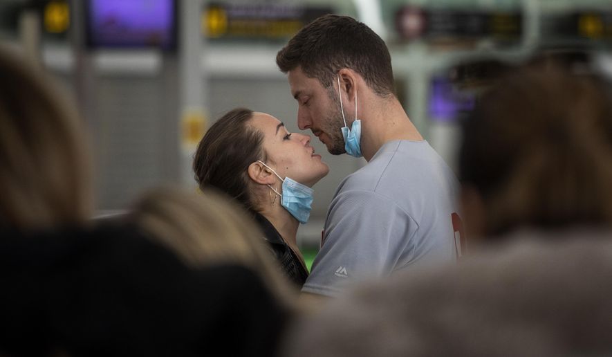 A couple kiss,  at the Barcelona airport, Spain, Thursday, March 12, 2020. President Donald Trump, who had downplayed the coronavirus for weeks, suddenly struck a different tone, announcing strict rules on restricting travel from much of Europe to begin this weekend. For most people, the new coronavirus causes only mild or moderate symptoms, such as fever and cough. For some, especially older adults and people with existing health problems, it can cause more severe illness, including pneumonia. (AP Photo/Emilio Morenatti)
