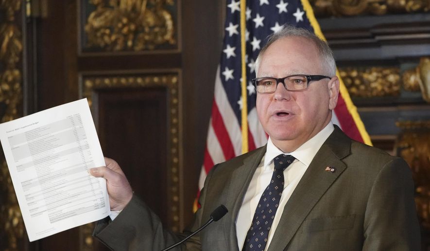 Gov. Tim Walz holds up his supplemental budget on Thursday, March 12, 2020, which is scaled back due to the unexpected demand for spending on the coronavirus response. The Governors press conferences are now being live streamed on Facebook Live along with ASL interpreters in response to the coronavirus outbreak. The Governor is exploring new ways to continue to communicate with Minnesotans, even if access to the Capitol is scaled back. (Glen Stubbe/Star Tribune via AP)