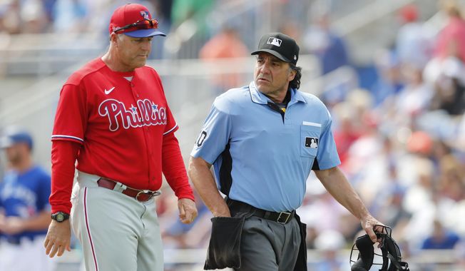 FILE - In this March 8, 2020, file photo, Philadelphia Phillies&#x27; pitching coach Bryan Price walks with umpire Phil Cuzzi during a spring training baseball game, Sunday,, in Dunedin, Fla. Price could end up being the most valuable addition the Phillies made in the offseason if he can get some talented members of the staff to reach their potential.(AP Photo/Carlos Osorio, File)