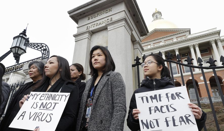 Jessica Wong, of Fall River, Mass., front left, Jenny Chiang, of Medford, Mass., center, and Sheila Vo, of Boston, from the state's Asian American Commission, stand together during a protest, Thursday, March 12, 2020, on the steps of the Statehouse in Boston. Asian American leaders in Massachusetts condemned what they say is racism, fear-mongering and misinformation aimed at Asian communities amid the widening coronavirus pandemic that originated in China. (AP Photo/Steven Senne)