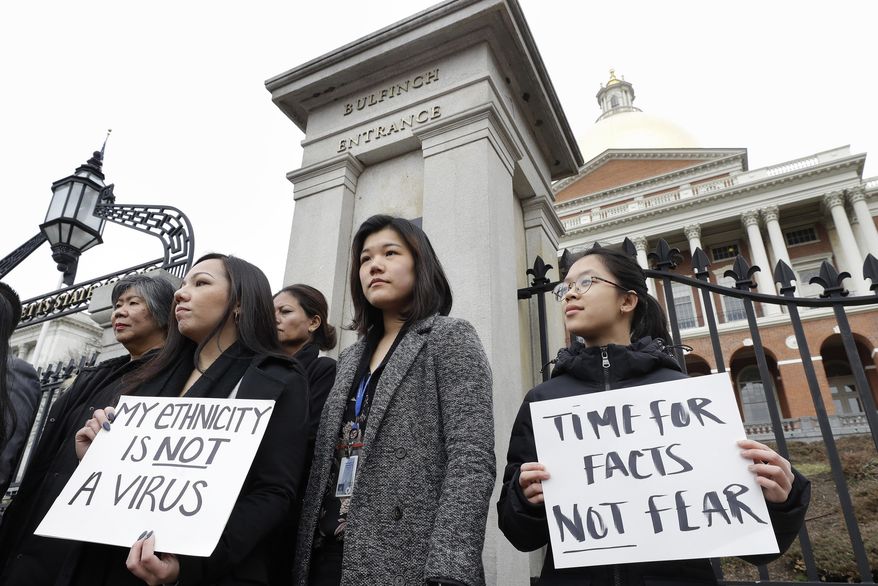 Jessica Wong, of Fall River, Mass., front left, Jenny Chiang, of Medford, Mass., center, and Sheila Vo, of Boston, from the state's Asian American Commission, stand together during a protest, Thursday, March 12, 2020, on the steps of the Statehouse in Boston. Asian American leaders in Massachusetts condemned what they say is racism, fear-mongering and misinformation aimed at Asian communities amid the widening coronavirus pandemic that originated in China. (AP Photo/Steven Senne)