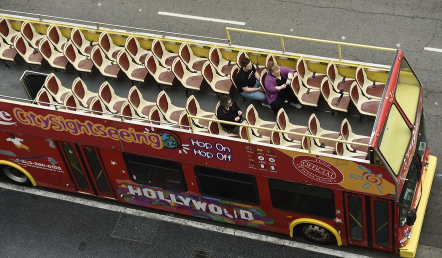 Passengers sit in a mostly empty sightseeing bus on Hollywood Boulevard, Thursday, March 12, 2020, in the Hollywood section of Los Angeles. (AP Photo/Chris Pizzello)