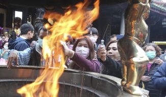 People wear face masks to protect against the spread of the coronavirus as they pray at the popular Longshan Temple in Taipei, Taiwan, Thursday, March 12, 2020. For most people, the new coronavirus causes only mild or moderate symptoms. For some it can cause more severe illness. (AP Photo/Chiang Ying-ying)