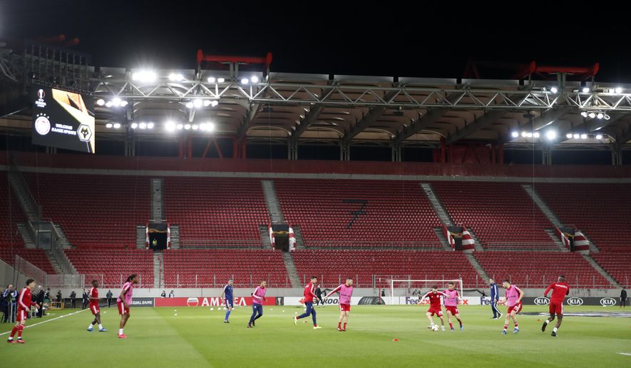 Olympiakos players challenge for the ball during warm up prior the Europa League round of 16 first leg soccer match between Olympiakos and Wolverhampton Wanderers at the Karaiskakis Stadium in Piraeus, Greece, Thursday, March 12, 2020. The match is being played in an empty stadium because of the coronavirus outbreak. (AP Photo/Thanassis Stavrakis)