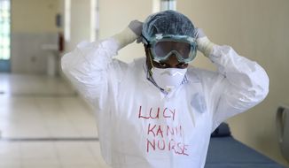 FILE - In this Friday, March 6, 2020 file photo, Kenyan nurse Lucy Kanyi, with her name written on her protective clothing so she can be recognized when wearing it, demonstrates to media the facilities and protective equipment to be used to isolate and treat coronavirus cases, at the infectious disease unit of Kenyatta National Hospital in the capital Nairobi, Kenya. Authorities in Kenya said Friday, March 13, 2020, that a Kenyan woman who recently traveled from the United States via London has tested positive for the new COVID-19 coronavirus, the first case in the East African country. For most people, the new coronavirus causes only mild or moderate symptoms, such as fever and cough. For some, especially older adults and people with existing health problems, it can cause more severe illness, including pneumonia. (AP Photo/Patrick Ngugi, File)
