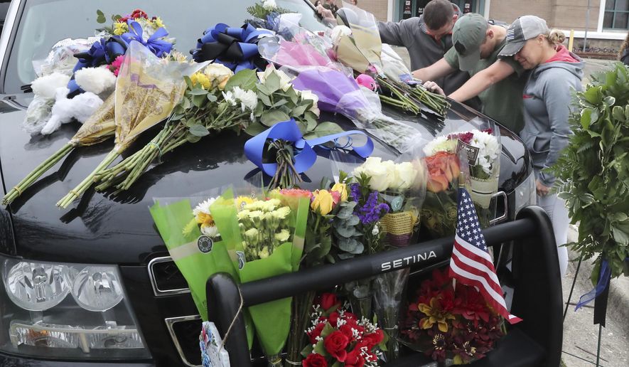 From left, Hot Springs police Officer Shawn Woodall, Officer Cody Rollins and Officer 1st Class Shannon Steed bow their heads in a moment of prayer beside the police unit of Officer 1st Class Brent Scrimshire, who was shot and killed during a traffic stop. (Richard Rasmussen/The Sentinel-Record via AP)