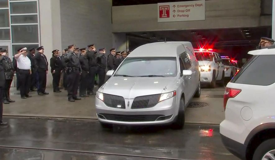 In this image provided by WPVI-TV 6ABC, police officers salute as the hearse carrying the body of Philadelphia police officer Cpl. James O'Çonnor leaves the hospital on Friday, March 13, 2020 in Philadelphia. O'Çonnor was shot and killed early Friday as he served a homicide warrant at a home in the city's Frankford section. (WPVI-TV 6ABC via AP)