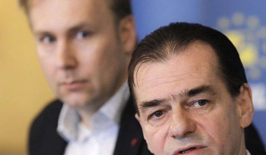 Romania's health minister Victor Costache, left, watches as caretaker prime minister of Romania, Ludovic Orban speaks during a press conference in Bucharest, Romania, Friday, March 13, 2020 after it was confirmed that a senator who attended several meetings in the building tested positive for the infection. The caretaker prime minister of Romania, Ludovic Orban, said in a press conference at the parliament, the government, including all ministers, as well as the leadership of the ruling National Liberal Party and all its senators, are going into quarantine after one of the governing party's senators, who took part in high-level meetings, who confirmed to be infected with the coronavirus. (AP Photo/George Calin)