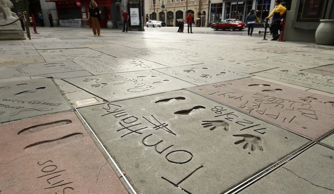 The cement inscription of actor Tom Hanks sits in the nearly empty forecourt of the TCL Chinese Theatre, Thursday, March 12, 2020, in the Hollywood section of Los Angeles. Hanks and his wife, actress-singer Rita Wilson, have tested positive for the coronavirus, the actor said in a statement Wednesday. For most people, the new coronavirus causes only mild or moderate symptoms. For some it can cause more severe illness. (AP Photo/Chris Pizzello)