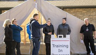Director of Safety and Security Derec Styer, center, talks to other employees during an training session on Thursday, March 12, 2020, at Gritman Medical Center in Moscow, Idaho. The training allowed employees to practicing setting up a tent that can be used for drive-up non-emergency screening for COVID-19 coronavirus. (Geoff Crimmins/Moscow-Pullman Daily News via AP) (Geoff Crimmins/Moscow-Pullman Daily News via AP)