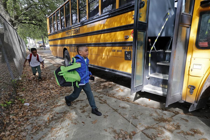 Childern board a school bus after school was adjourned at the Dr. Martin Luther King, Jr. Elementary School for Science and Technology in New Orleans, Friday, March 13, 2020. Louisiana Gov. John Bel Edwards on Friday closed K-12 public schools across the state for roughly a month and banned gatherings of more than 250 people in an effort to slow the spread of the coronavirus. He said he also planned to postpone the presidential primary until June. (AP Photo/Gerald Herbert)
