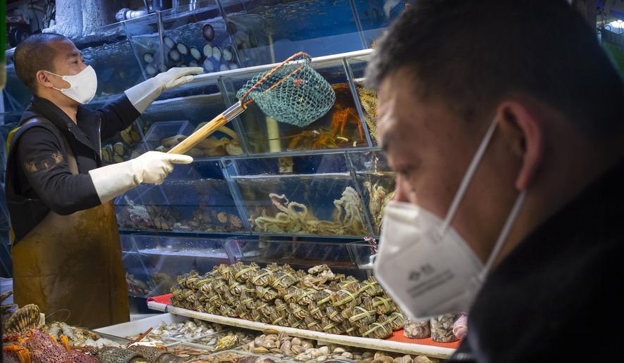 A customer wears a face mask as he shops for seafood at a market in Beijing, Saturday, March 14, 2020. The United States declared a state of emergency Friday as many European countries went on a war footing amid mounting deaths as the world mobilized to fight the widening coronavirus pandemic. For most people, the new coronavirus causes only mild or moderate symptoms, such as fever and cough. For some, especially older adults and people with existing health problems, it can cause more severe illness, including pneumonia. (AP Photo/Mark Schiefelbein)