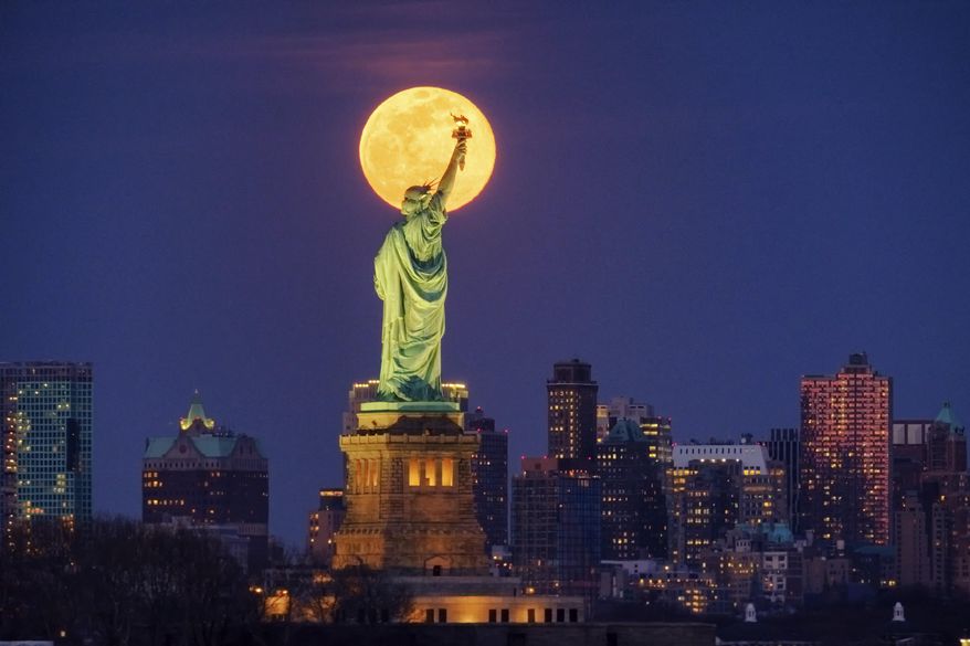 The rising full moon shines behind the Statue of Liberty, Monday evening, March 9, 2020, in New York City. (AP Photo/J. David Ake)
