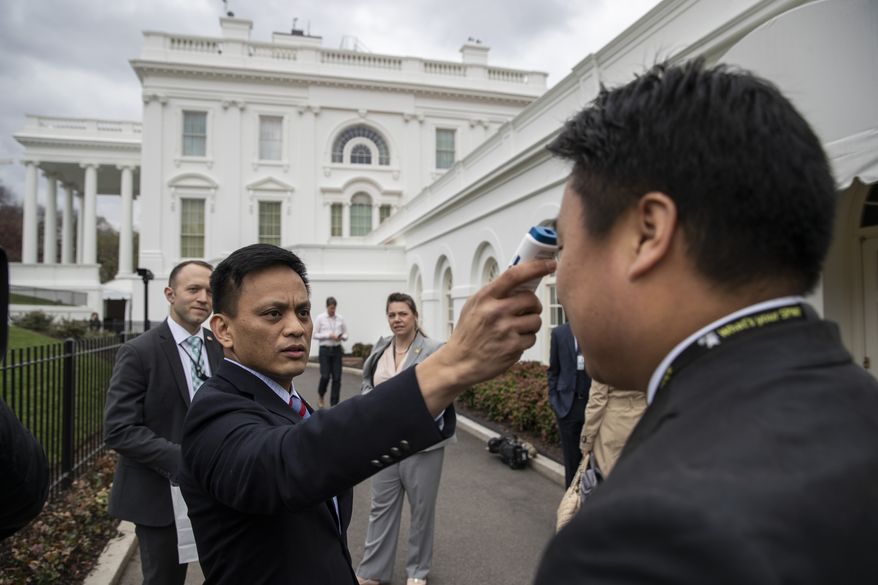 A member of the media, right, gets their temperature taken by member of the White House physicians office, over concerns about the coronavirus at the White House, Sunday, March 15, 2020, in Washington. (AP Photo/Alex Brandon)