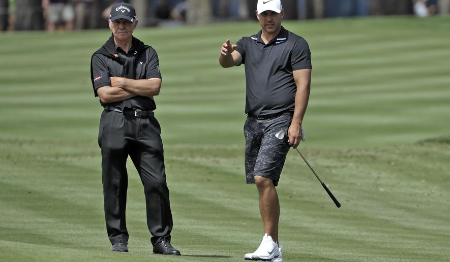 Brooks Koepka, right, gestures as he talks to his short game coach Peter Cowen during a practice round for The Players Championship golf tournament Wednesday, March 11, 2020, in Ponte Vedra Beach, Fla. (AP Photo/Chris O'Meara)