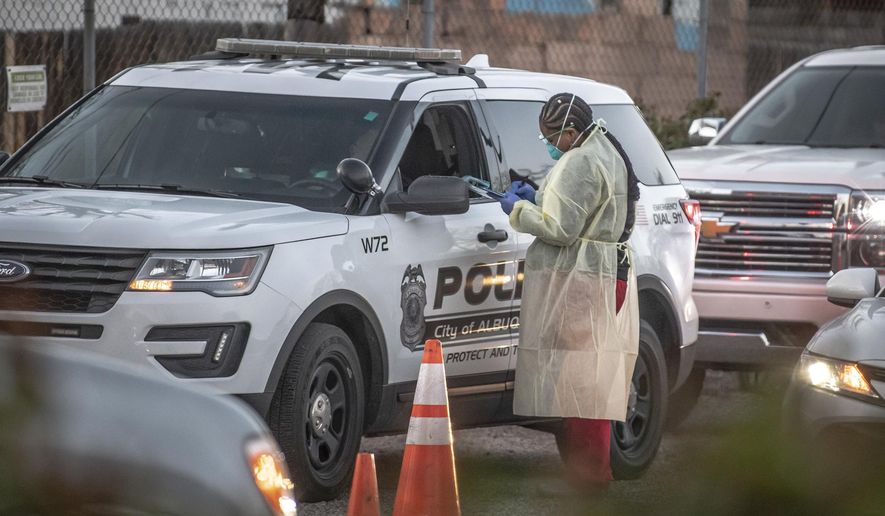 Medical personnel prepare to check people at a mobile site for coronavirus testing across the street from Lovelace Hospital on Friday afternoon, March 13, 2020, in Albuquerque, N.M, (Roberto E. Rosales/The Albuquerque Journal via AP)