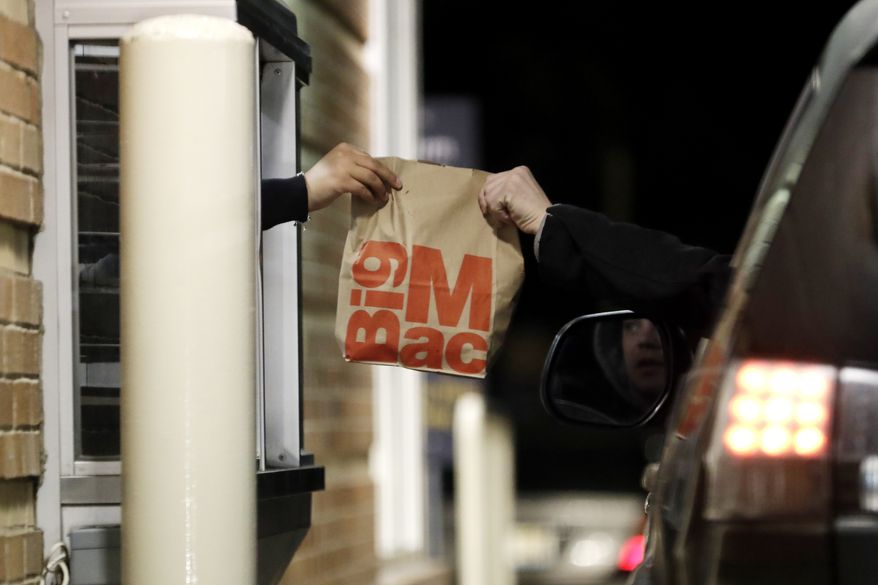 A customer, right, picks up his food at a McDonald in Wheeling, Ill., Sunday, March 15, 2020. Illinois Gov. J.B. Pritzker on Sunday ordered all bars and restaurants in the state to close starting Monday night, March 16 through March 30. (AP Photo/Nam Y. Huh)