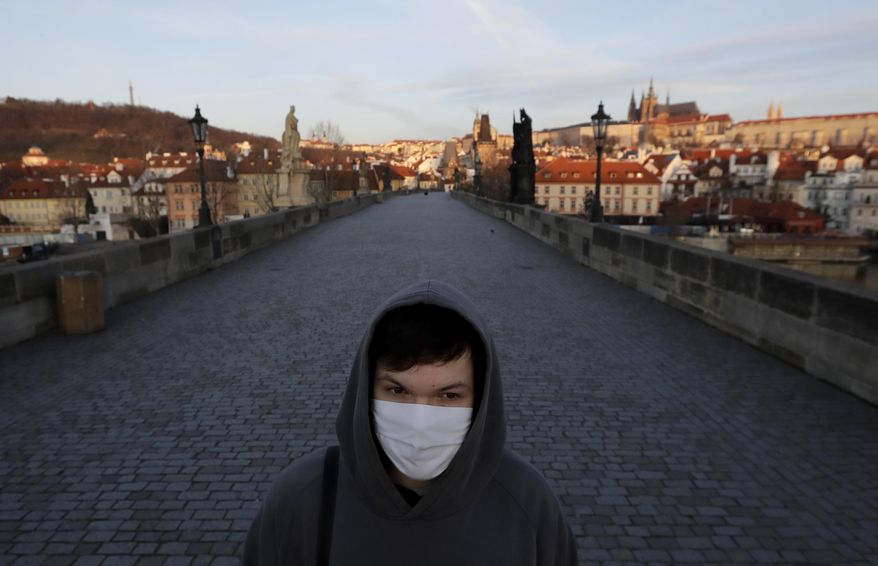 A young man wearing a face mask walks across an empty Charles Bridge in Prague, Czech Republic, Monday, March 16, 2020. The Czech government has imposed further dramatic restrictions on the movement in efforts to contain the outbreak of the coronavirus. Prime Minister Andrej Babis said the government is declaring a quarantine for the entire country, an unprecedented measure in his country&#39;s history that became effective on Monday. For most people, the new coronavirus causes only mild or moderate symptoms. For some it can cause more severe illness. (AP Photo/Petr David Josek)