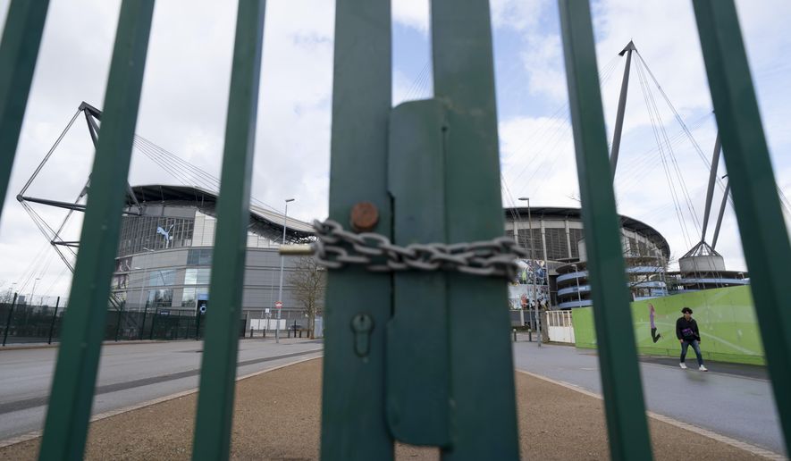 A locked gate is seen by the Etihad Stadium where Manchester City was due to play Burnley in an English Premier League soccer match Saturday March 14, 2020, after all English soccer games were cancelled due to the spread of the COVID-19 Coronavirus. For most people, the new COVID-19 coronavirus causes only mild or moderate symptoms, but for some it can cause more severe illness.(AP Photo/Jon Super)