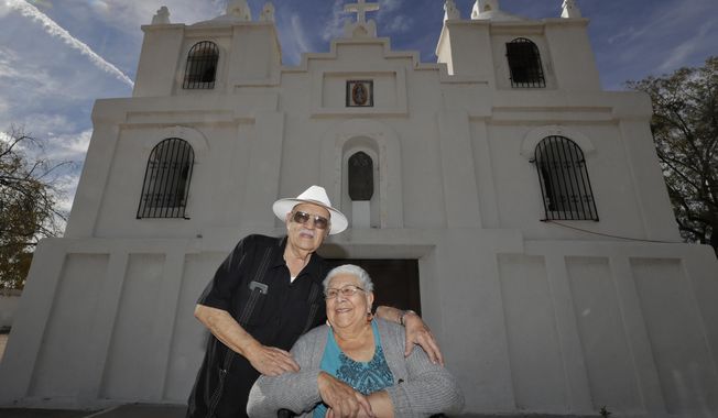Frank and Ester Cota pose for a photograph outside Our Lady of Guadalupe church Friday, Jan. 24, 2020 in Guadalupe, Ariz. Founded by Yaqui Indian refugees from Mexico more than a century ago, Guadalupe is named for Mexico&#x27;s patron saint, Our Lady of Guadalupe, and is fiercely proud of its history. The town known for sacred Easter rituals featuring deer-antlered dancers also is wary of outsiders as it prepares for the 2020 census. (AP Photo/Matt York)