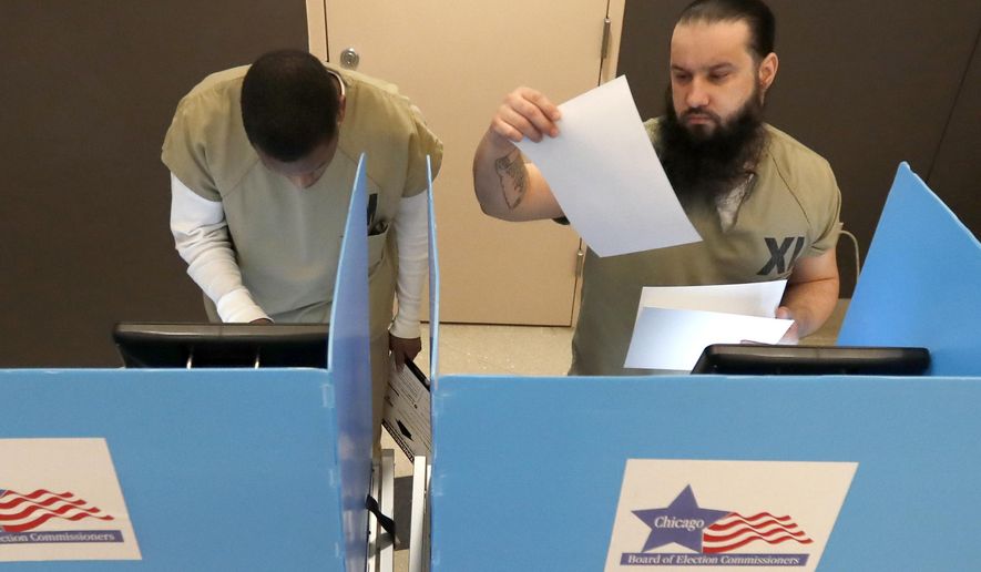 In this Saturday, March 14, 2020 photo, Cook County jail inmates Vincent Smith, left, and Ioan L'ela participate in early voting for the March 17, Illinois primary at the jail in Chicago. (AP Photo/Charles Rex Arbogast)