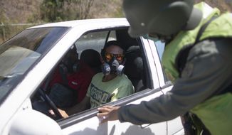 A man wearing a mask talks to a solider checking vehicles entering  Caracas, Venezuela, Monday, March 16, 2020. President Nicolás Maduro ordered Sunday residents in the capital of Caracas and six states to stay home under a quarantine in a bid to control the spread of the coronavirus According to the World Health Organization, most people recover in about two to six weeks from the virus, depending on the severity of the illness. (AP Photo/Ariana Cubillos)