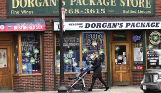 A woman pushes a stroller past a liquor store on a nearly empty sidewalk on Broadway on St. Patrick&#39;s Day in the South Boston neighborhood of Boston, Tuesday, March 17, 2020. For most people, the new coronavirus causes only mild or moderate symptoms. For some, it can cause more severe illness, especially in older adults and people with existing health problems. (AP Photo/Charles Krupa)