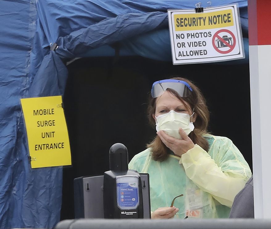 A nurse stands outside the entrance to the mobile surge unit tent for coronavirus testing outside the emergency entrance at WellStar Kennestone Hospital for patients who are being tested for COVID-19 on Tuesday, March 17, 2020, in Mariett, Ga. (Curtis Compton/Atlanta Journal-Constitution via AP(