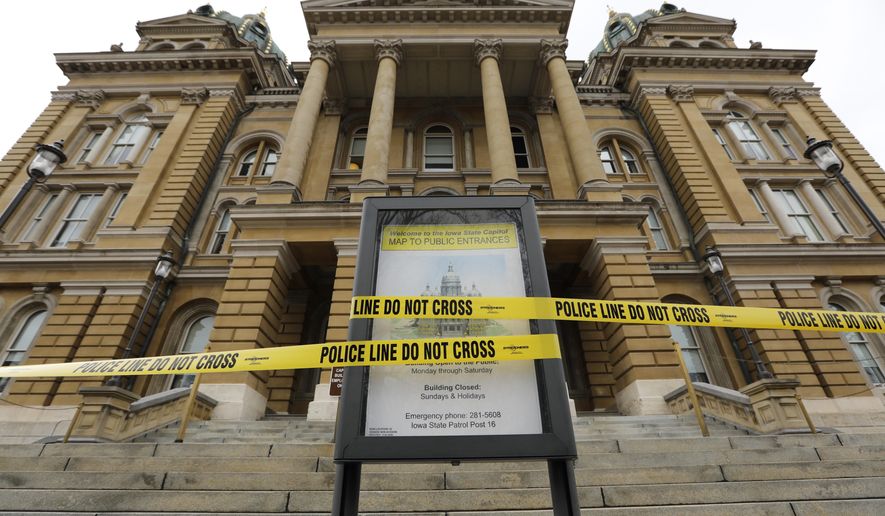 Police tape is wrapped around a sign in front of a closed entrance, Monday, March 16, 2020, at the Statehouse in Des Moines, Iowa. Iowa leaders are suspending the current legislative session for at least 30 days after learning the state now has community spread of coronavirus. (AP Photo/Charlie Neibergall)