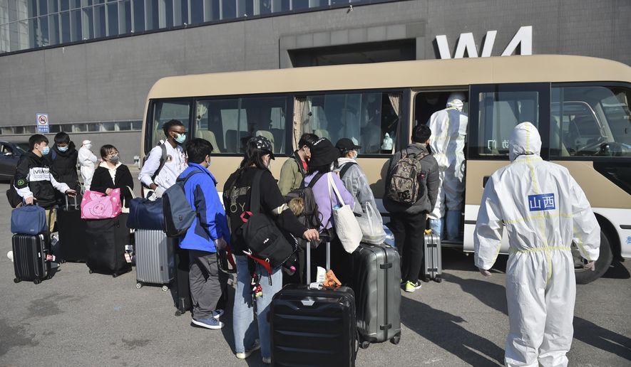 In this March 17, 2020, photo released by China&#39;s Xinhua News Agency, workers in protective suits watch as travelers board a shuttle bus at the New China International Exhibition Center, which has been converted into a facility to screen international flight passengers arriving in Beijing. As the pandemic expanded its reach, China and South Korea were trying to hold their hard-fought gains. China is quarantining new arrivals, who in recent days have accounted for an increasing number of cases, and South Korea starting Thursday will increase screenings of all overseas arrivals. The virus causes only mild or moderate symptoms, such as fever and cough, for most people, but severe illness is more likely in the elderly and people with existing health problems. (Peng Ziyang/Xinhua via AP)