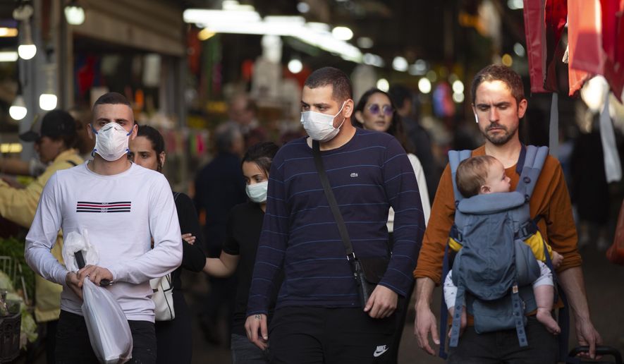 People wear face masks as they shop at a food market in Tel Aviv, Israel, Monday, March 16, 2020. Israel imposed sweeping travel and quarantine measures the government ordered restaurants, malls, cinemas, gyms and daycare centers shut to contain the spread of the coronavirus. For most people, the new coronavirus causes only mild or moderate symptoms. For some it can cause more severe illness. (AP Photo/Oded Balilty)