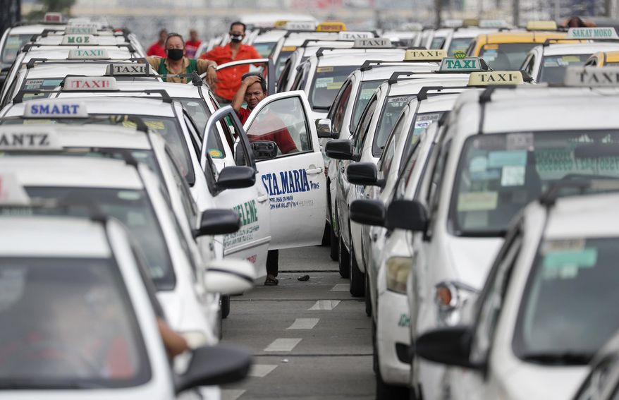 A taxi driver reacts as they wait to show their ID and car documents to police who instructed them to stop operations while the government implements localized quarantining as a precautionary measure against the spread of the new coronavirus in Manila, Philippines, early Tuesday, March 17, 2020. For most people, the new coronavirus causes only mild or moderate symptoms. For some, it can cause more severe illness, especially in older adults and people with existing health problems. (AP Photo/Aaron Favila)