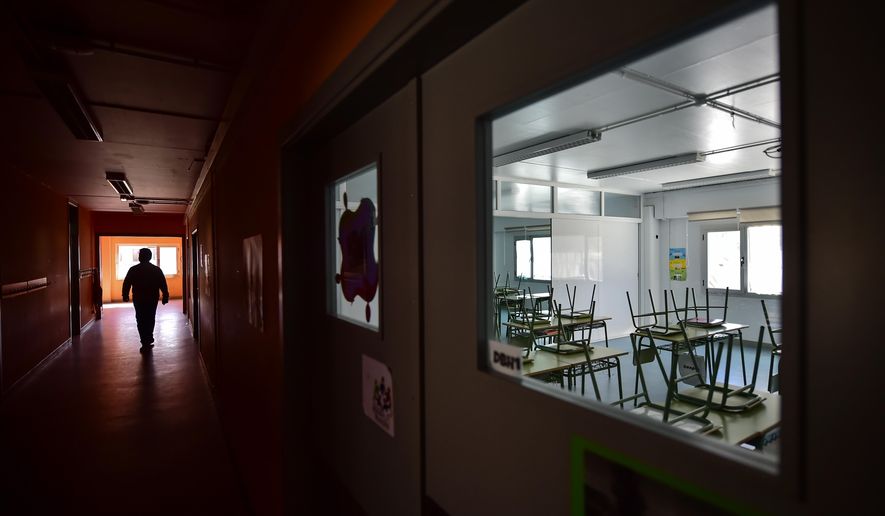 A teacher walks along a hallway of an empty public school in small Spanish Basque village of Labastida, northern Spain, March 11, 2020. (AP Photo/Alvaro Barrientos)