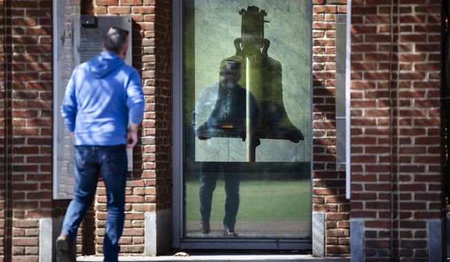 A visitor views the Liberty Bell from outside as the center is temporarily closed for cleaning in Philadelphia, Monday, March 16, 2020.  In a new front to slow the spread of the new coronavirus in Pennsylvania, Gov. Tom Wolf ordered all restaurants and bars to close their dine-in facilities in five heavily populated counties starting Monday. According to the World  Health Organization, most people recover in about two to six weeks, depending on the severity of the illness.  (AP Photo/Matt Rourke)