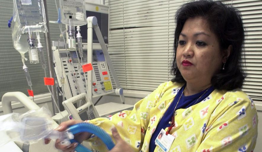 In this May 25, 2005, file photo, Lovely R. Suanino, a respiratory therapist at Newark Beth Israel Medical Center in Newark, N.J., demonstrates setting up a ventilator in the intensive care unit of the hospital. U.S. hospitals bracing for a possible onslaught of coronavirus patients with pneumonia and other breathing difficulties could face a critical shortage of mechanical ventilators and health care workers to operate them. (AP Photo/Mike Derer, File)