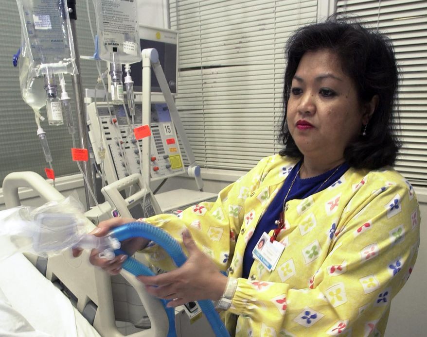 In this May 25, 2005, file photo, Lovely R. Suanino, a respiratory therapist at Newark Beth Israel Medical Center in Newark, N.J., demonstrates setting up a ventilator in the intensive care unit of the hospital. U.S. hospitals bracing for a possible onslaught of coronavirus patients with pneumonia and other breathing difficulties could face a critical shortage of mechanical ventilators and health care workers to operate them. (AP Photo/Mike Derer, File)