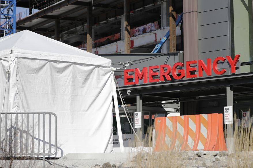 A tent stands at the emergency entrance to Seattle Children's hospital Wednesday, March 18, 2020, in Seattle. Health officials across Washington state are scrambling to secure hospital beds, staff and critical supplies as the number of people sickened by the new coronavirus continues to grow. Washington has about 13,000 hospital beds, which won't be enough to support the expected surge in COVID-19 cases, so officials are implementing a list of measures to expand capacity. (AP Photo/Elaine Thompson)