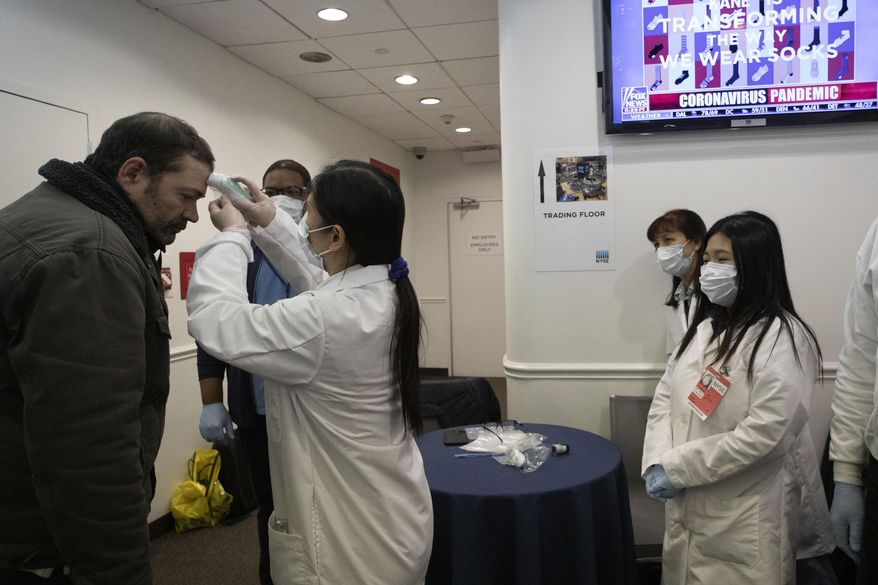 Health care workers screen people entering the New York Stock Exchange, Wednesday, March 18, 2020. Global stock markets have sunk in a third day of wild price swings after President Donald Trump promised to prop up the U.S. economy through the coronavirus outbreak. (AP Photo/Mark Lennihan)