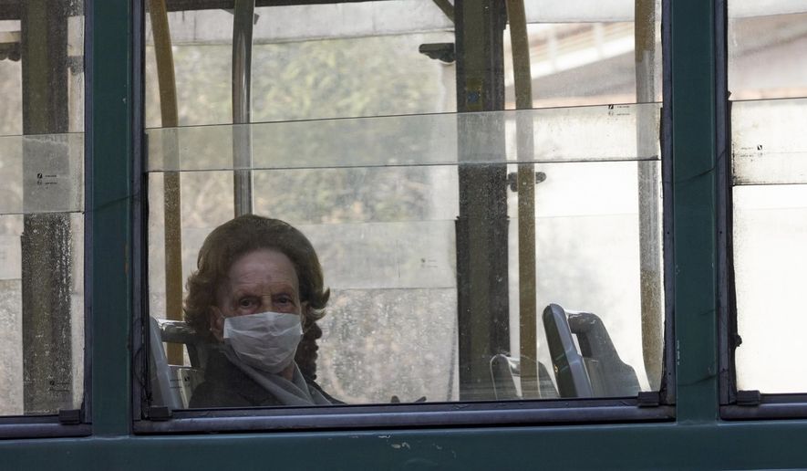 A woman wears a protective mask as she rides in a tram, in Rome, Wednesday, March 18, 2020. For most people, the new coronavirus causes only mild or moderate symptoms. For some it can cause more severe illness, especially in older adults and people with existing health problems. (AP Photo/Andrew Medichini)